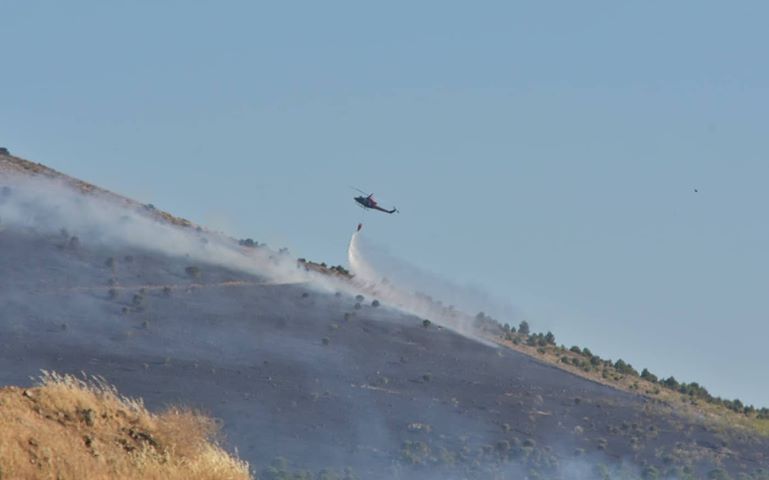 burguillos Un helicóptero de extinción de incendios descarga sobre la ladera incendiada.