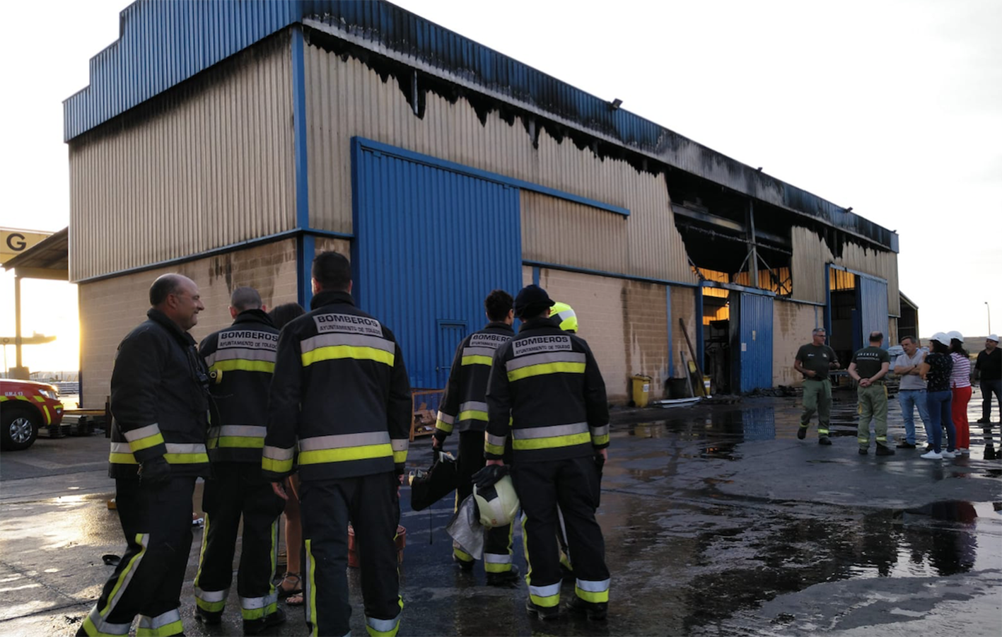 Un grupo de Bomberos de Toledo, junto a la nave incendiada, tras apagar las llamas.