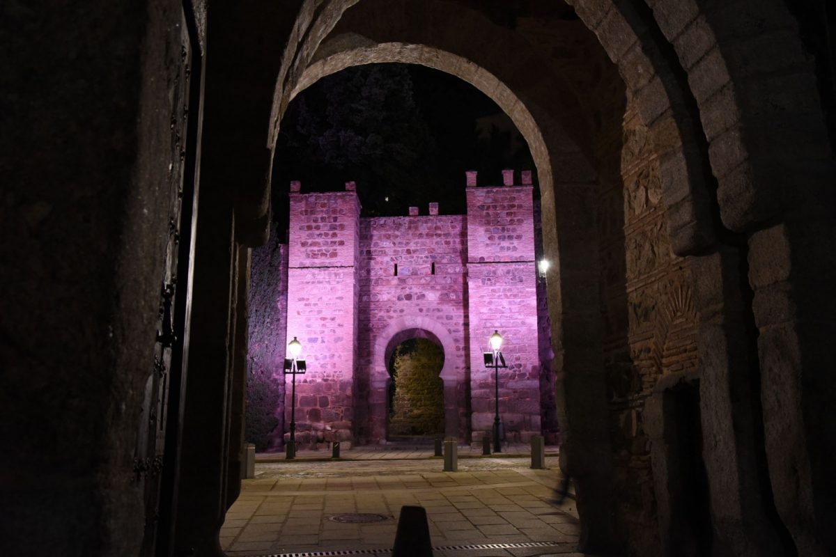 El puente de Alcántara iluminado de morado.