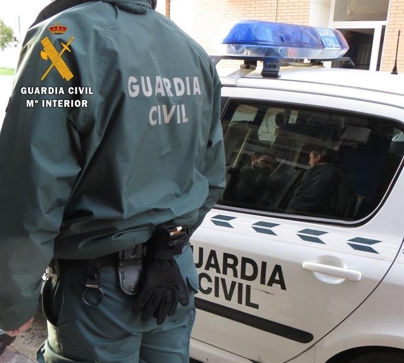 Agente y coche de la Guardia Civil.