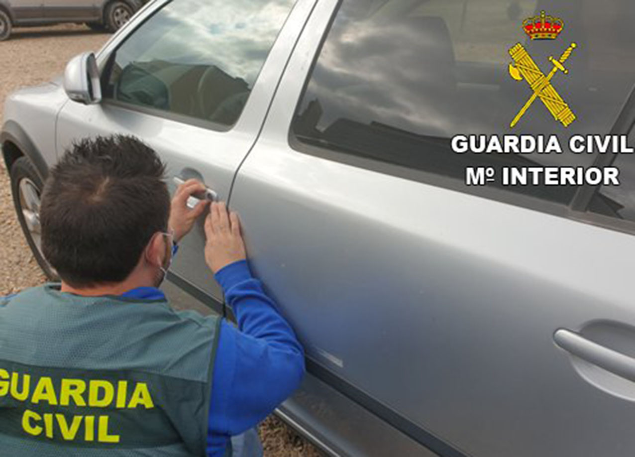Un agente de la Guardia Civil inspecciona el bombín de una puerta de uno de los coches en los que robaron.