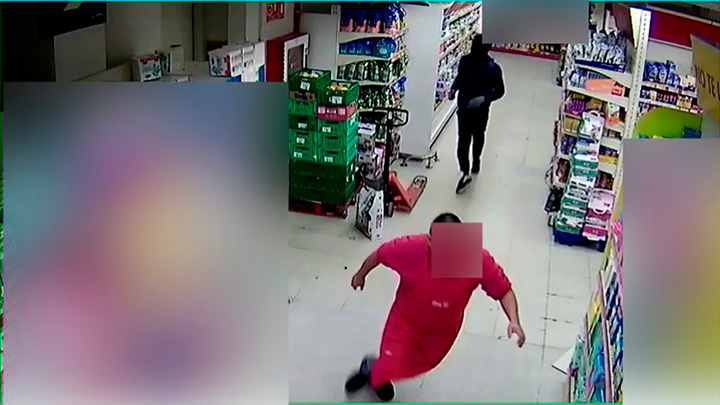Un empleado huye de uno de los ladrones que entraron en el supermercado.