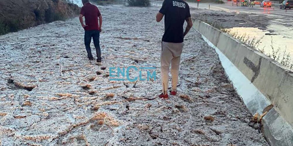 Dos personas, caminando sobre la manta de granizo que inhabilitó la vía de servicio de la N-401, en el término municipal de Burguillos.