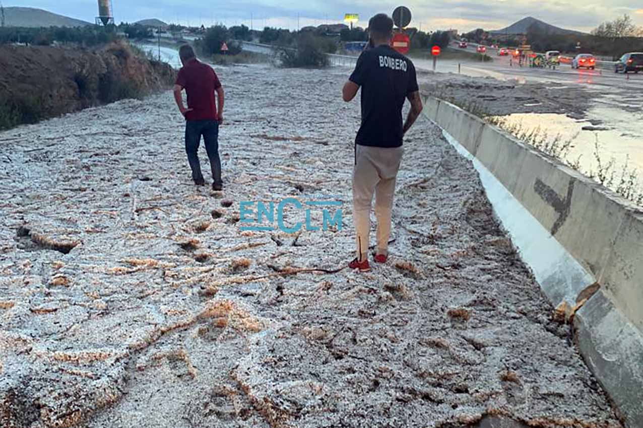 Dos personas, caminando sobre la manta de granizo que inhabilitó la vía de servicio de la N-401, en el término municipal de Burguillos.