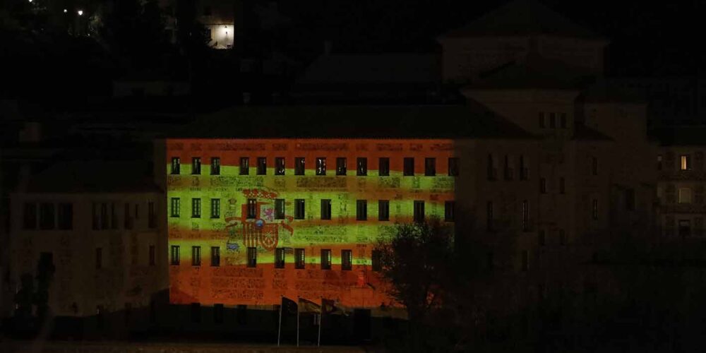 Una ondeante bandera española sobre la fachada principal de las Cortes regionales.