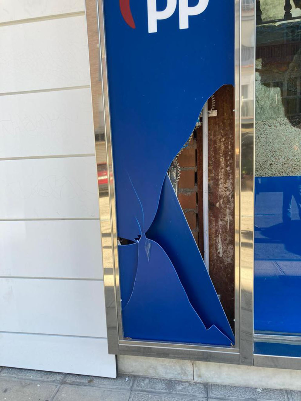 Así ha quedado el plástico de la fachada de la sede del PP en Toledo después de que alguien le pegara una patada.