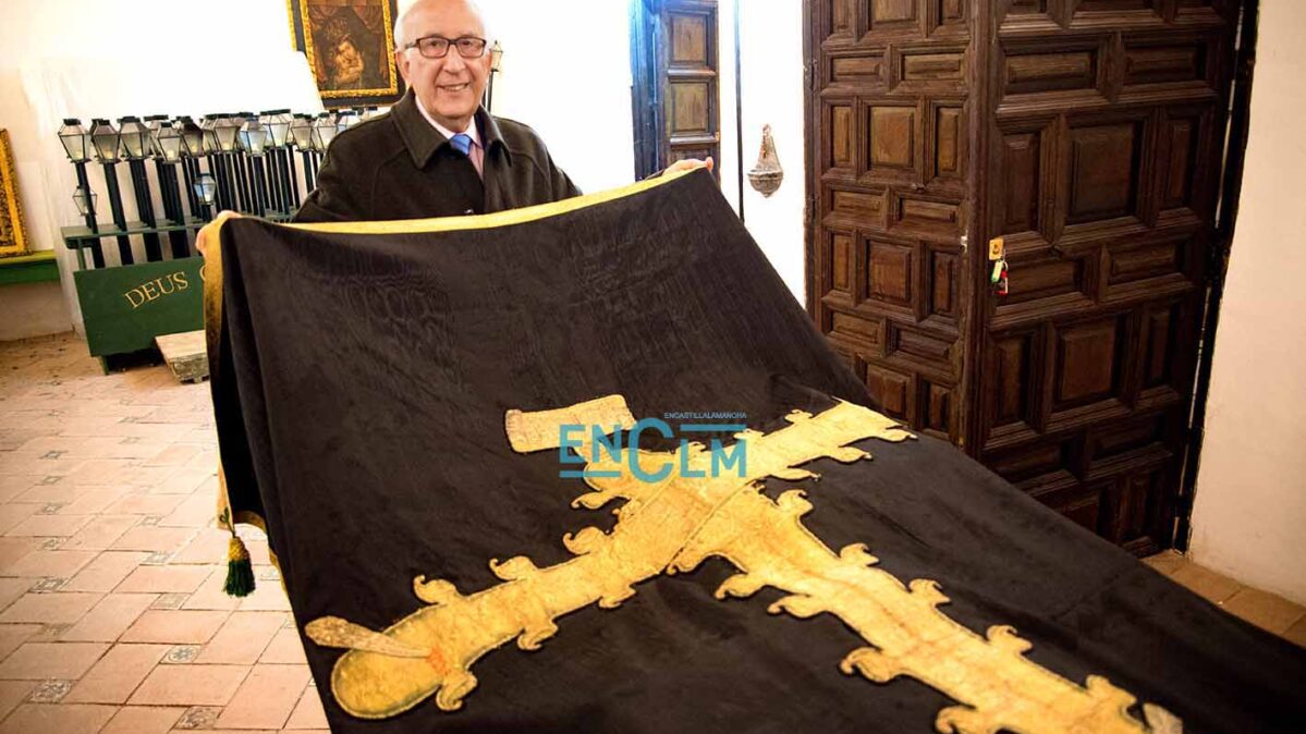 Fernando Lorenzana, hermano mayor de la cofradía, junto al Paño de la Caridad que data de hace dos siglos y que se conserva en muy buen estado. Aunque en la procesión sale otro más actual. Foto: Rebeca Arango.