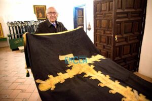 Fernando Lorenzana, hermano mayor de la cofradía, junto al Paño de la Caridad que data de hace dos siglos y que se conserva en muy buen estado. Aunque en la procesión sale otro más actual. Foto: Rebeca Arango.