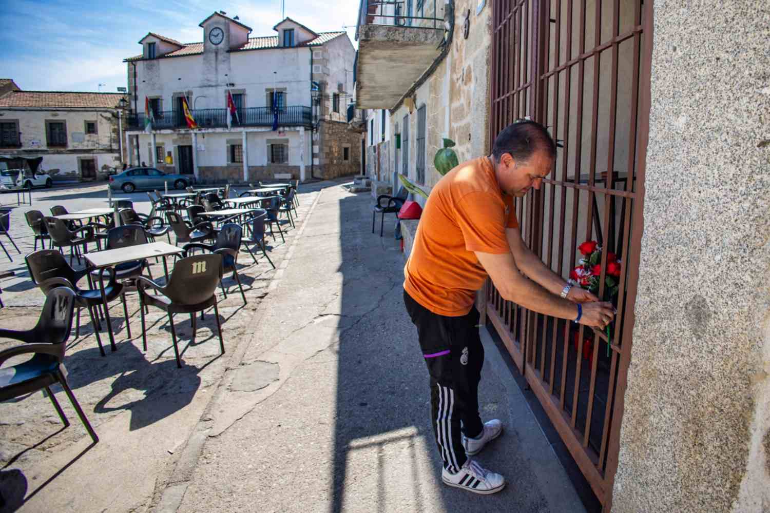 En la imagen un vecino coloca unas flores en la puerta del domicilio de la víctima, en Pelahustán. EFE/Ángeles Visdómine.