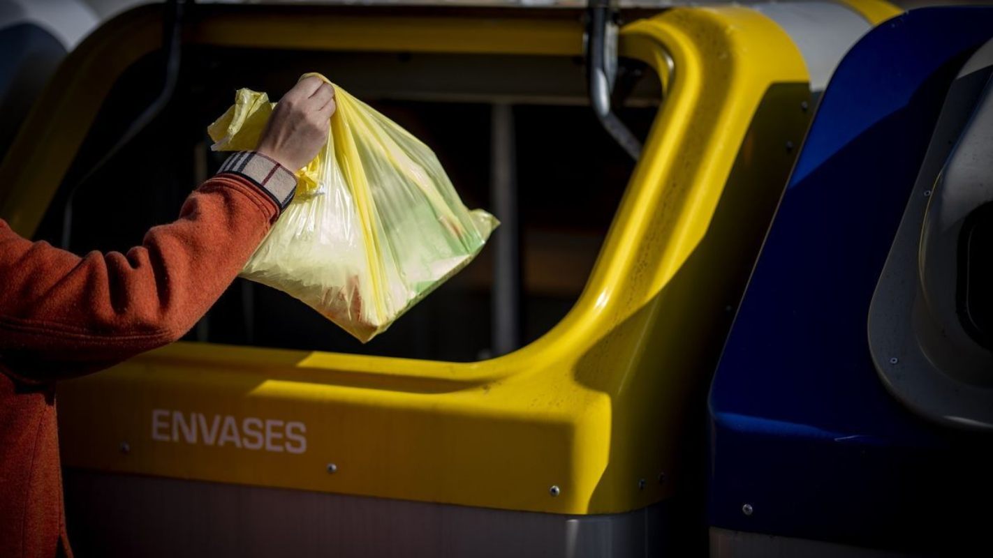 Una persona reciclando en un contenedor amarillo