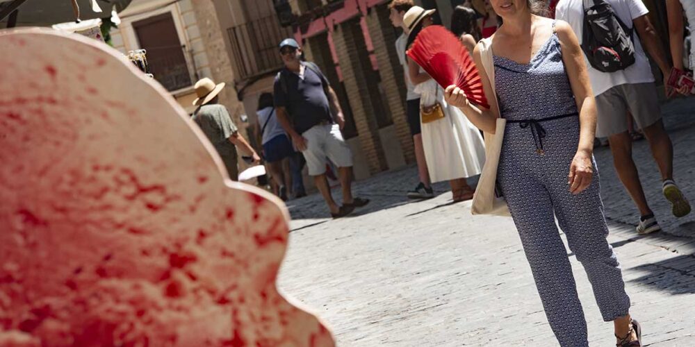 Mujer se abanica para protegerse del calor en Toledo