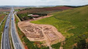 Imagen aérea de la parte excavada del Cerro de las Cabezas. Al fondo, su centro de interpretación