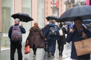 Viandantes protegiéndose de la lluvia.