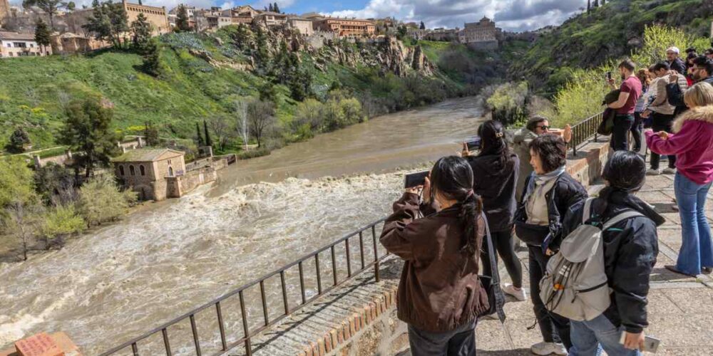 Turistas y curiosos fotografían la subida del Tajo en Toledo. Foto: EFE/Ángeles Visdómine.