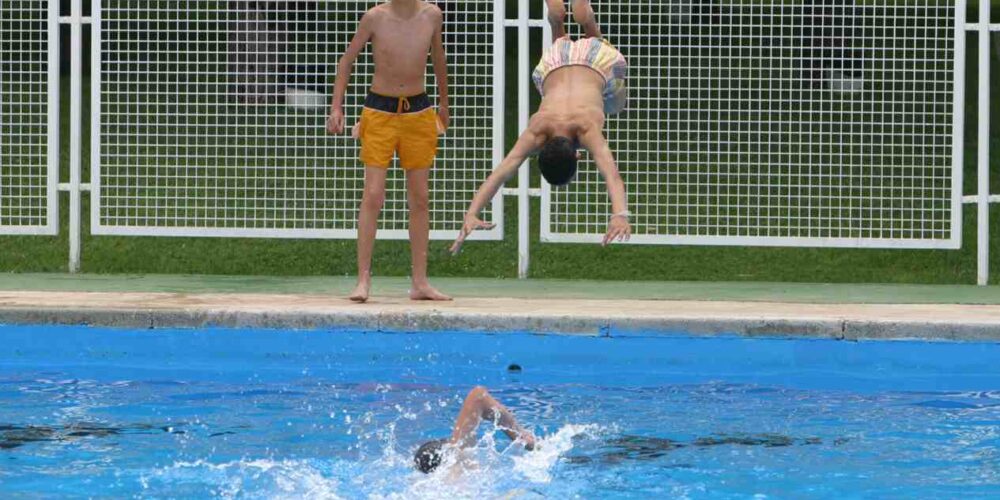 Un chico tirándose de cabeza a una piscina