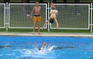 Un chico tirándose de cabeza a una piscina