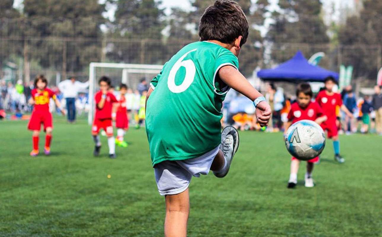 Un niño de las escuelas deportivas de iniciación, jugando al fútbol.