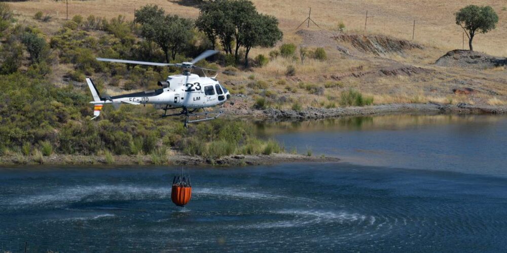 Un helicóptero recoge agua de una balsa de agua en la Finca Montón de Trigo, donde se originó el fuego